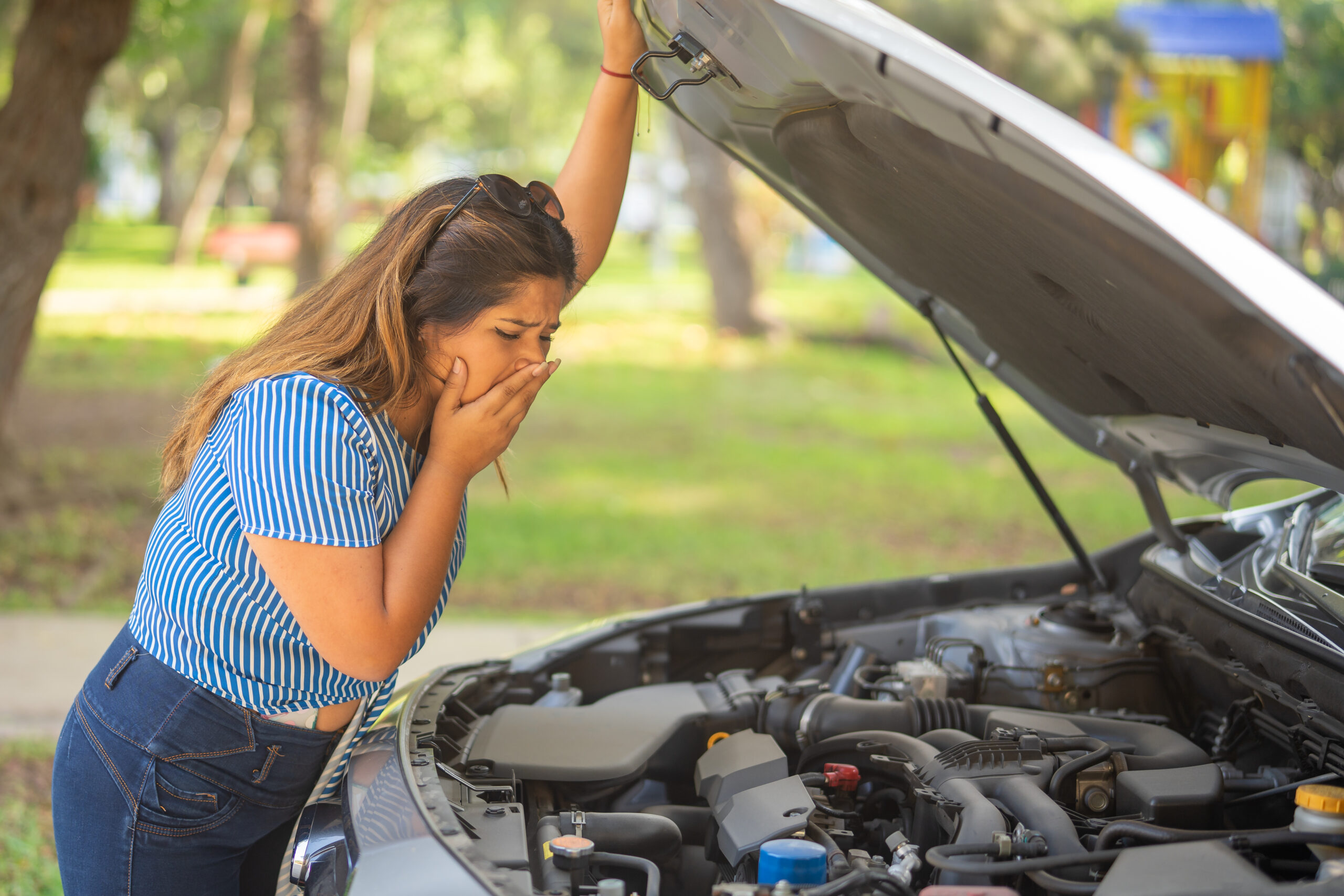 Car radiator overheating with steam under the hood in summer heat, indicating need for radiator flush and cooling system service